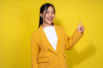 A woman in a yellow jacket is smiling and giving a thumbs up