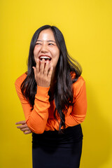 A woman in an orange shirt is laughing and making a face