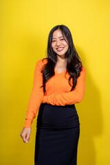 A woman in an orange shirt and black skirt is smiling for the camera