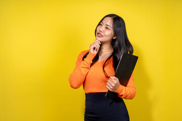 Naklejka premium A woman in an orange shirt and black skirt is holding a book