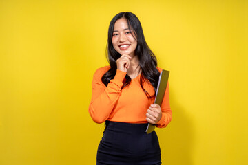 A woman in an orange shirt and black skirt is holding a book
