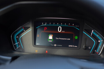 Close-up tire pressure low indicator displays on instrument panel of modern car minivan in Parking mode, tire pressure monitoring system TPMS indicates lights on driver information interface
