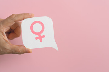 hand hold pink female gender sign on real white speech bubble paper cut background. For women's...