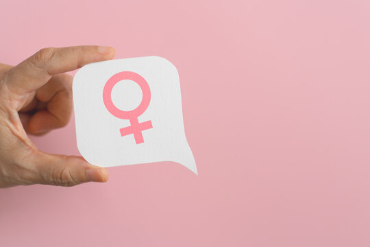 hand hold pink female gender sign on real white speech bubble paper cut background. For women's power, voice, feminism concept, including copy space - Powered by Adobe