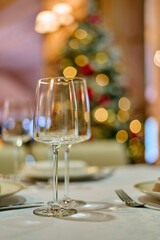 Christmas festive modern restaurant interior with greenery, pleasant cozy lighting and festive table setting with glasses.
