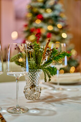 Christmas festive modern restaurant interior with greenery, pleasant cozy lighting and festive table setting with glasses.