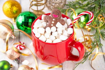 Funny Christmas hot chocolate with marshmallow and chocolate gingerbread man taking chocolate bath in red mug, on festive holiday decorated  background