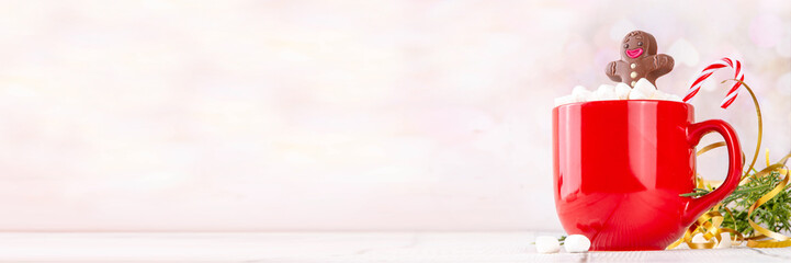 Funny Christmas hot chocolate with marshmallow and chocolate gingerbread man taking chocolate bath in red mug, on festive holiday decorated  background