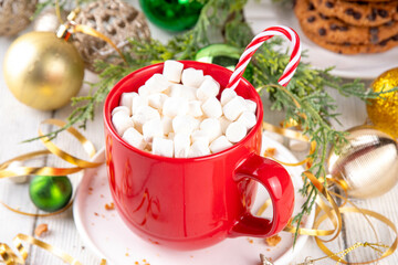 Festive red mug of hot chocolate or latte with marshmallow, for Christmas morning, warm cozy holiday drink on Christmas New Year decorated shiny background