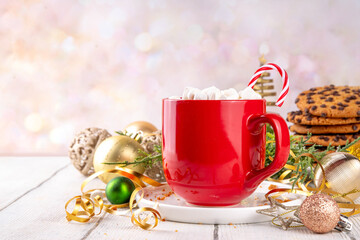 Festive red mug of hot chocolate or latte with marshmallow, for Christmas morning, warm cozy holiday drink on Christmas New Year decorated shiny background