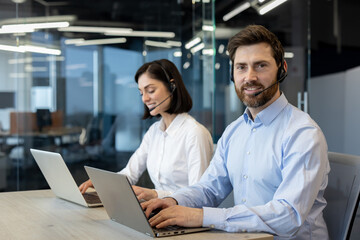 Customer service representatives using headsets and laptops in office. Focused on customer support, teamwork, and professionalism. Showcasing modern workspace and effective communication skills.