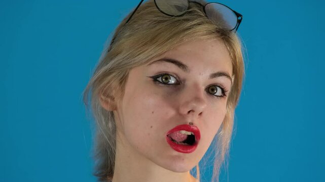 Charismatic model opens mouth and runs tongue over upper teeth. Woman with serious expression puts piercing between teeth slow motion