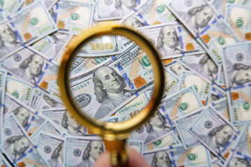 100 dollar banknote and magnifying glass
