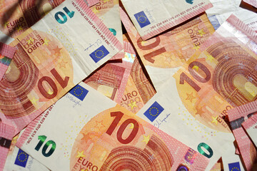 A close-up photo of 10 (ten) euro notes randomly laid out on a table. Paying bills in Europe with cash: small denomination paper money prepared for various payments.