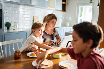 Mother eating breakfast with her kids on kitchen table