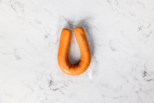 Top view of a traditional dutch smoked sausage that is vacuum packed in plastic on a marble background.
