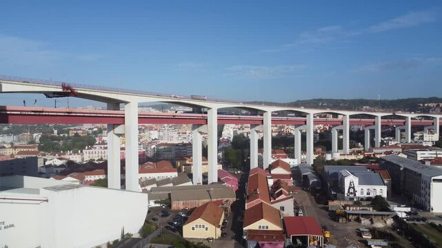 A Ponte 25 de Abril ergue-se majestosamente sobre as &aacute;guas brilhantes do Rio Tejo, com a sua estrutura vermelha ic&ocirc;nica resplandecendo sob o sol intenso. 