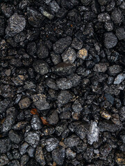 Coal. The dark texture is black. Background image of anthracite coal. The surface of natural black coal. A grade of high-quality metallurgical coal anthracite. Black background. Vertical image.