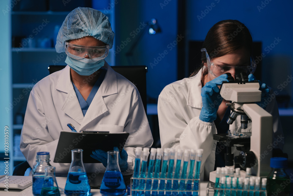 Wall mural team of biochemical research scientists working with a microscope for vaccine development