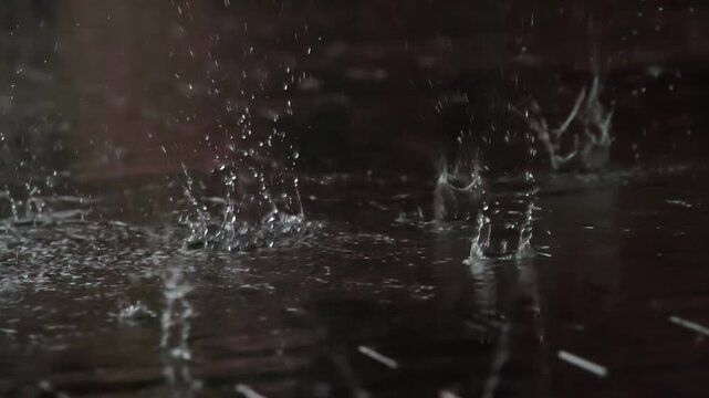 Drops of Rain Fall on the Sidewalk. Drops of rain fall from the roof onto a granite paving slab