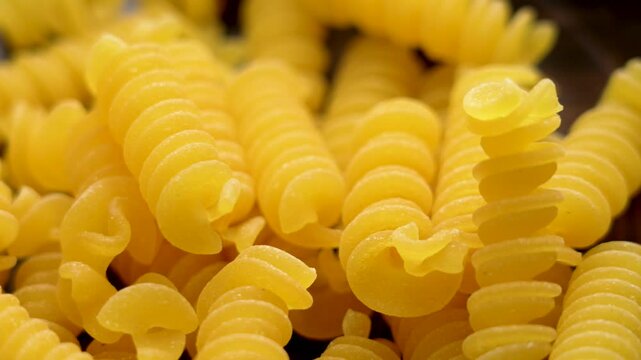 Colorful Italian uncooked fusilli pasta with delightful texture. Macro shot. Rotation