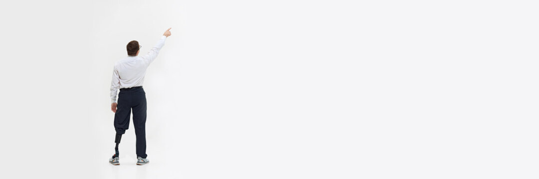 Man with prosthetic leg pointing upwards, symbolizing ambition and pursuit of goals. Overcoming challenges in a supportive work environment. Concept of business, dei, equality, support