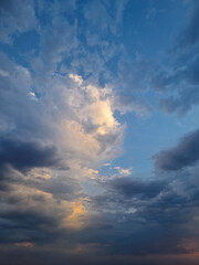 Sky view filled with dramatic clouds during sunset after the storm. Sunlight peeks through, creating a stunning and atmospheric cloudscape scene with vibrant colors and a sense of tranquility
