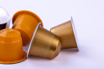 Assorted coffee capsules in different colors scattered across a plain white backdrop