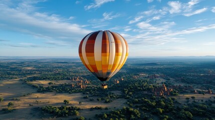 Fototapeta premium A large, colorful hot air balloon majestically floats over a vast and beautiful landscape, symbolizing exploration and freedom against a stunning backdrop of nature.