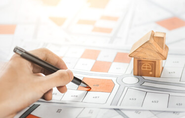 Woman holding a pencil pointing to cadastral map to decide to buy land. real estate concept with...