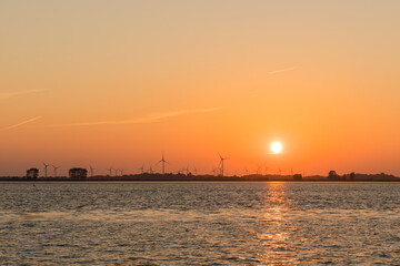Naklejka premium Sunset behind wind turbines near Wischhafen on the Elbe river shore