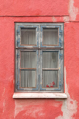 Wooden blue weathered window in red wall
