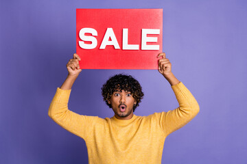 Photo of shocked man wear trendy yellow clothes arms above head hold red placard sale isolated on...