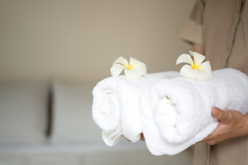 A hotel maid stacked towels on the bed and placed flowers on the towels in a hotel room