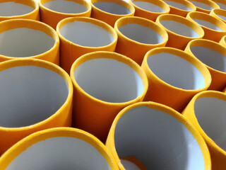 Obraz premium close up of a bunch of white pvc pipes with a layer of yellow velvet fabric. round plastic pipes in the craft industry