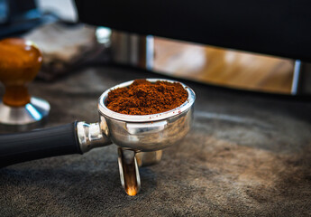 Close-up of ground coffee in portafilter or portable coffee filter handle and ground coffee for a coffee making machine on coffee shop