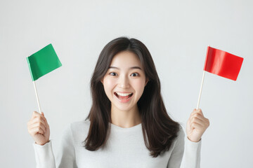 Young woman is smiling while holding a green and a red flag,representing healthy and unhealthy relationship boundaries