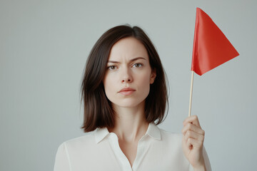 Young woman is holding a red flag as a sign of warning, looking seriously