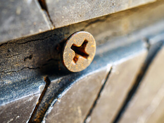 Close-up of a rusty screw driving into a car tire causing a puncture.