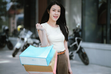 A stylish young woman walks confidently around the city with shopping bags in hand. She spends the day shopping comfortably, looking relaxed and happy.