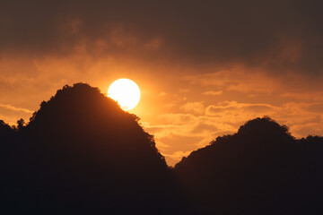 Vibrant sunset with orange sky over silhouette mountain