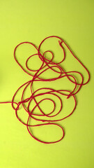 A Piece of knitting with color threads ball of yarn and a knitting needle on red background.