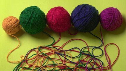 A Piece of knitting with color threads ball of yarn and a knitting needle on red background.