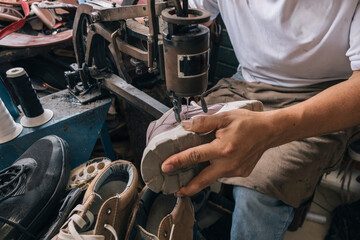 A skilled artisan carefully stitching the sole of a shoe using a traditional sewing machine in a...