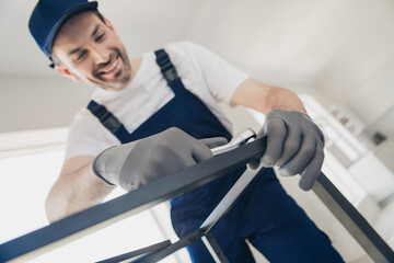 Smiling handyman in blue overalls performs house renovation with tools showcasing professional home...