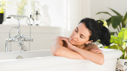 Obraz premium Relaxing mature middle-aged beautiful woman taking bath after hard-working day at home. Spa procedures in bathroom.