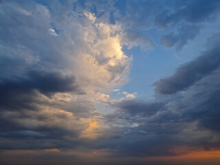 Sky view filled with dramatic clouds during sunset after the storm. Sunlight peeks through, creating a stunning and atmospheric cloudscape scene with vibrant colors and a sense of tranquility