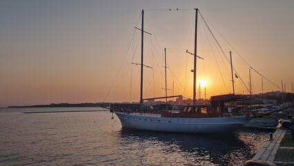 Sailboat docked at a marina during sunset. The warm sky reflects on the calm water. Tranquil beauty of a harbor at dusk, highlighting the serene end to a day in the old town of Nessebar