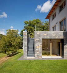Front view of a newly finished house with bedroom with direct access to the garden. To the left of the room, there is an external staircase.