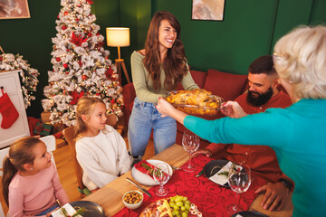 Women bringing food to the table for family Christmas dinner at home